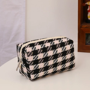 Detailed close-up of pink and black tweed plaid cosmetic bag with silver zipper closure