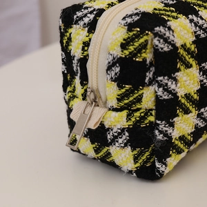 Detail of yellow houndstooth tweed cosmetic bag with silver metal zipper puller