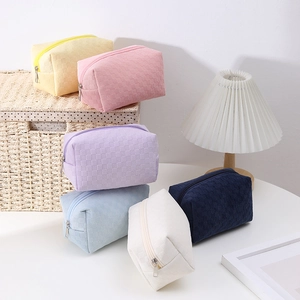 Detail of checkered pattern fabric makeup bags in six pastel colors on a white table
