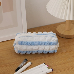 Detailed view of blue and white striped seersucker pencil case with ruffle edges on a desk