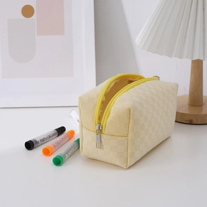 Detailed view of yellow checkered canvas pencil case with zipper on white desk