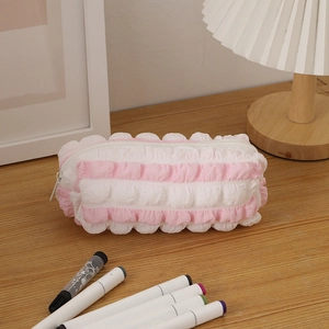 Detailed view of pink and white striped bubble texture pencil case on a wooden desk