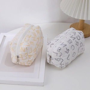 Close-up of quilted canvas makeup bags with letter print and metal zipper detail