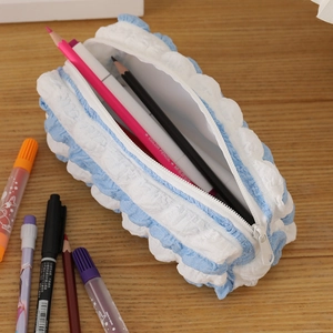 Detail view of large capacity blue puff textured pencil case on light wooden desk