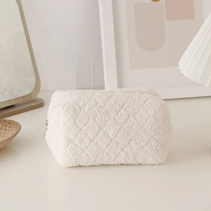 Close-up of a white plush pencil case featuring quilted texture and a gold metal zipper