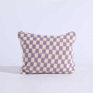 Detail of purple checkered knit makeup bag featuring a silver metal zipper closure
