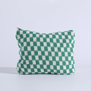 Detail of green and white checkered knit pouch featuring a silver metal zipper
