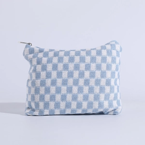 Detailed close-up of blue and white checkered knitted makeup bag with silver metal zipper