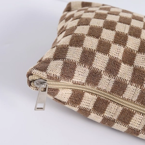 Close-up of knit checkerboard cosmetic bag with metal zipper and fabric texture