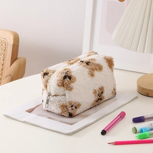 Close-up of soft plush makeup bag with brown teddy dog patterns on a white desk