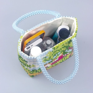 Handmade beaded handbag with floral forest pattern showing interior space for phone and makeup