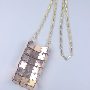 Close-up of rose gold square metal plates and geometric chain on a woven crossbody bag