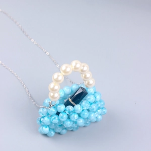 Detail of blue beaded mini bag with pearl handle, chain strap and lipstick for size