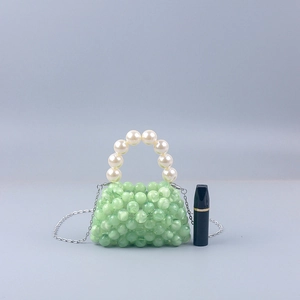 Mini green acrylic beaded bag with pearl handle and metal chain shown beside a lipstick