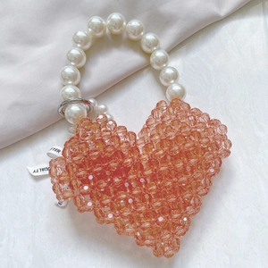 Detail of heart-shaped orange beaded mini bag with white faux pearl handle and metal ring