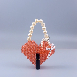 Macro view of heart-shaped woven bead handbag with pearl handle and ribbon detail