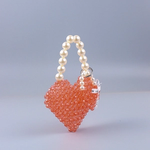 Detail of orange heart-shaped beaded handbag with pearl handle and silk ribbon