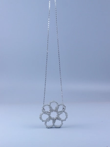Detailed view of a silver floral pendant made of small beads with a delicate cross chain