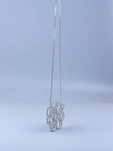 Macro shot of silver-toned beaded flower charm and chain with metallic reflections