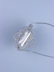 Close-up of silver hollowed flower necklace with transparent cylindrical pendant and fine chain
