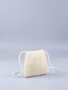 Détail d'un sac bandoulière fait main en perles blanches avec une texture tissée chic