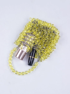 Detail view of yellow beaded handbag showing capacity with lipstick and beauty product