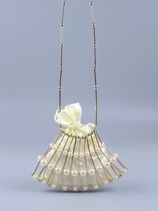 Close-up of fan-shaped pearl handbag with golden metal frame and satin drawstring pouch