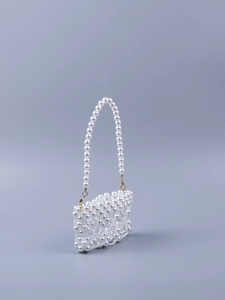 Detail of hand-woven imitation pearls and gold metal hooks on a mini white clutch bag
