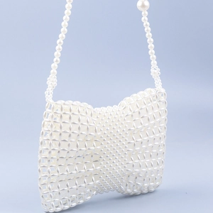 Détail de nœud en perles fait main sur un sac bandoulière blanc avec chaîne