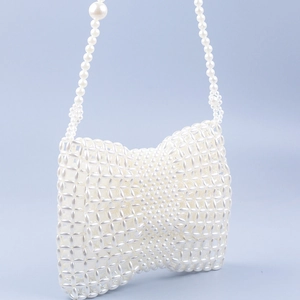Gros plan du sac à main artisanal en perles blanches avec nœud et bandoulière en perles