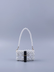 Detailed macro view of a handmade faux pearl woven mini bag with a lipstick for scale