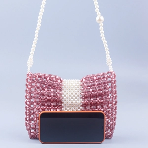 Détail du sac noeud rose fait main avec bandoulière en perles blanches et texture tissée