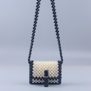 Detailed macro view showing a mini handmade pearl bag with lipstick for size comparison