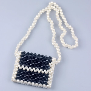 Close-up of handmade beaded mini bag with black beads and white pearl trim detail