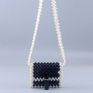 Mini handmade black and white pearl woven crossbody bag with lipstick for scale