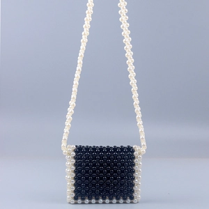 Detail of handcrafted mini beaded crossbody bag with black and white pearl weave texture