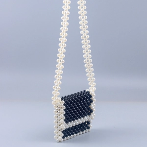 Detail of handmade mini acrylic crossbody bag with black and white pearl weave texture