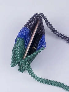 Détail du sac à bandoulière en perles montrant le rangement du téléphone et du rouge à lèvres