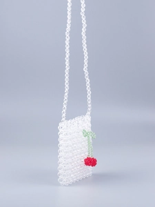 Détail du sac artisanal en perles acryliques avec décoration de breloque cerise rouge