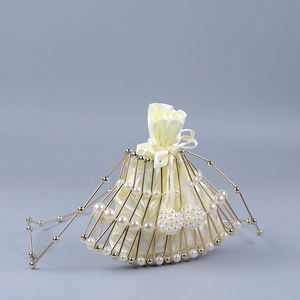 Close-up of golden fan-shaped metal frame with beaded pearls and satin drawstring bag