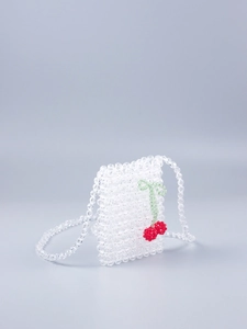 Détail macro du mini sac en perles acryliques tissé main avec motif cerise rouge
