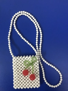 Détail du sac en perles acryliques avec décor cerises rouges sur tissage de perles blanches