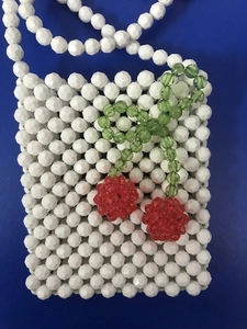 Vue détaillée d'un mini sac en perles acryliques fait main avec motif cerise sur fond bleu