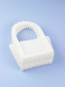 Macro detail of hand-woven pearl structure and smooth texture on U-shaped handbag