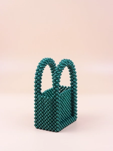 Detailed view of hand-woven dark green beaded handbag with metallic pearl finish and U-shaped handles