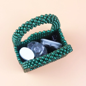 Detail of dark green pearl bead handbag showing interior capacity for small cosmetics