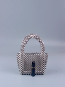 Detail of a handmade silver beaded evening bag with arc handle and metallic finish