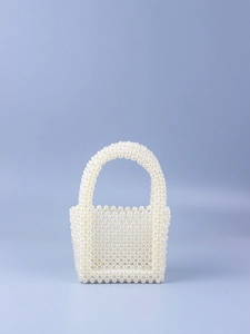 Detailed view of handmade pearl beaded handbag with U-shaped top handle and woven texture