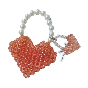 Handmade coral heart bead handbag with pearl handle and ribbon detail on white background