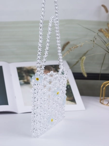 Detail of handmade clear acrylic beaded bag with blue floral accents and woven strap